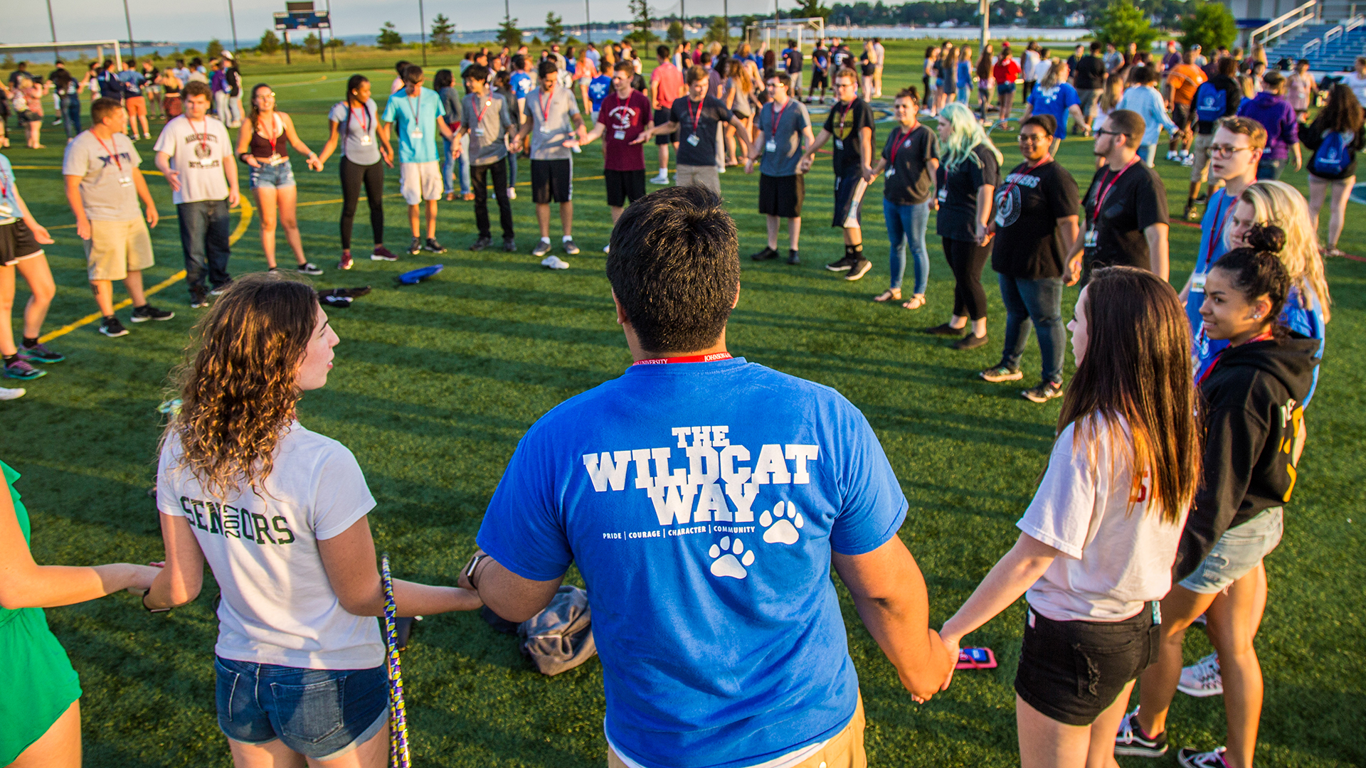 new student orientation, students stand in a circle doing icebreaker games.