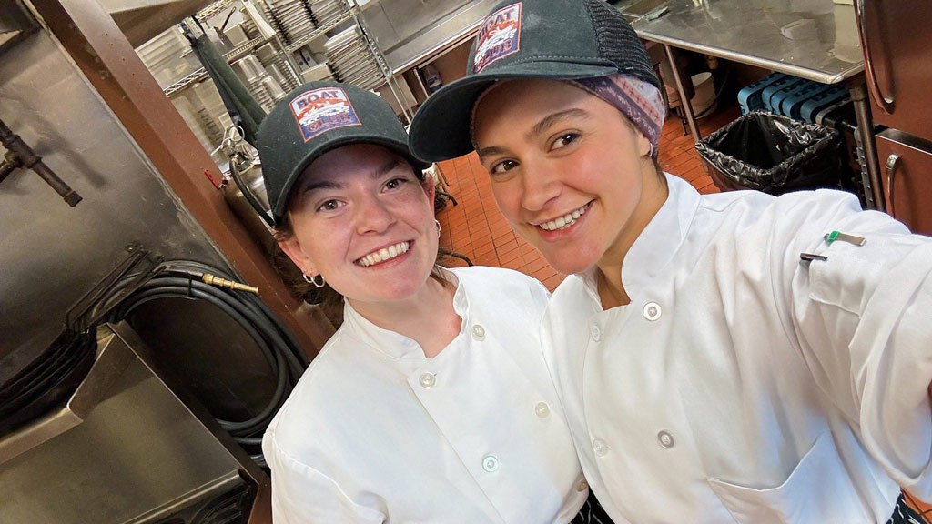 a photo of Carly McCrumb and Sophia Tingle taking a selfie in a restaurant kitchen