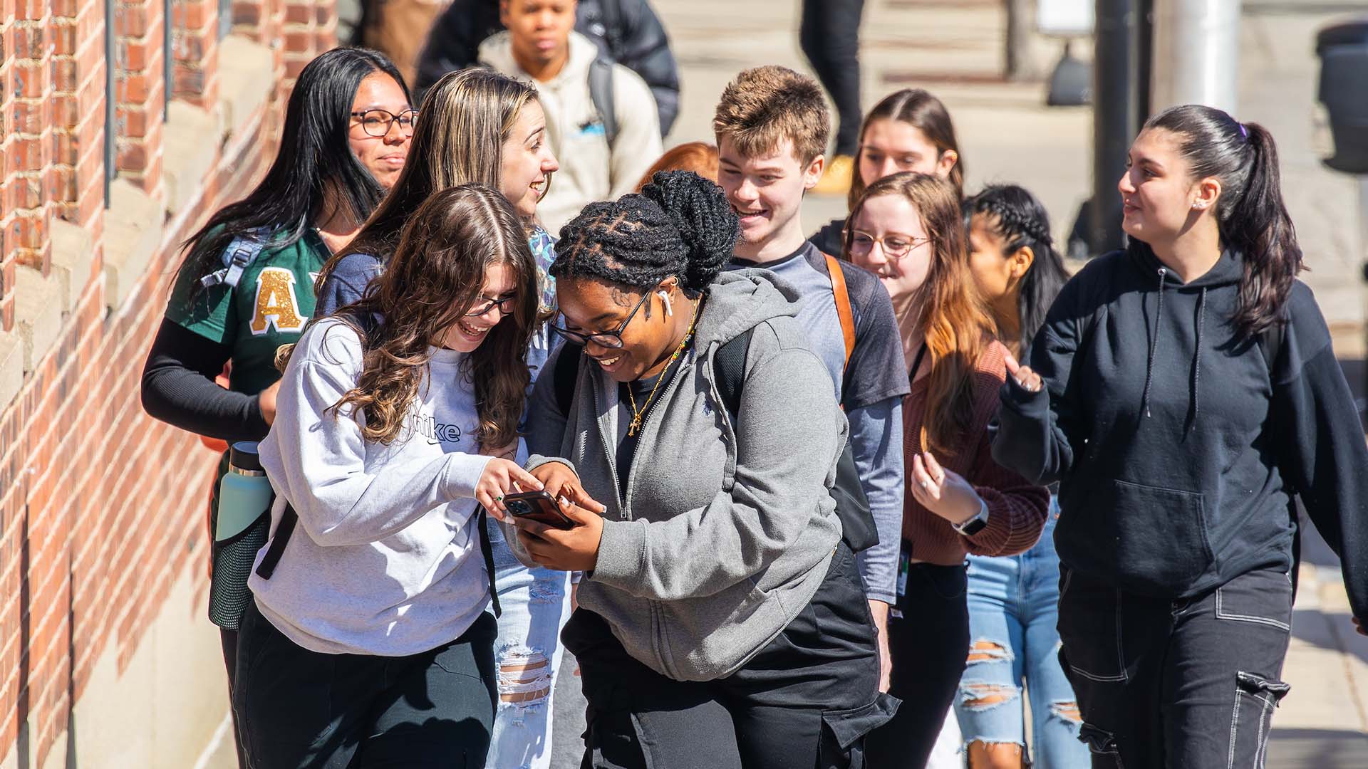 Students walking down the street while looking at a phone screen