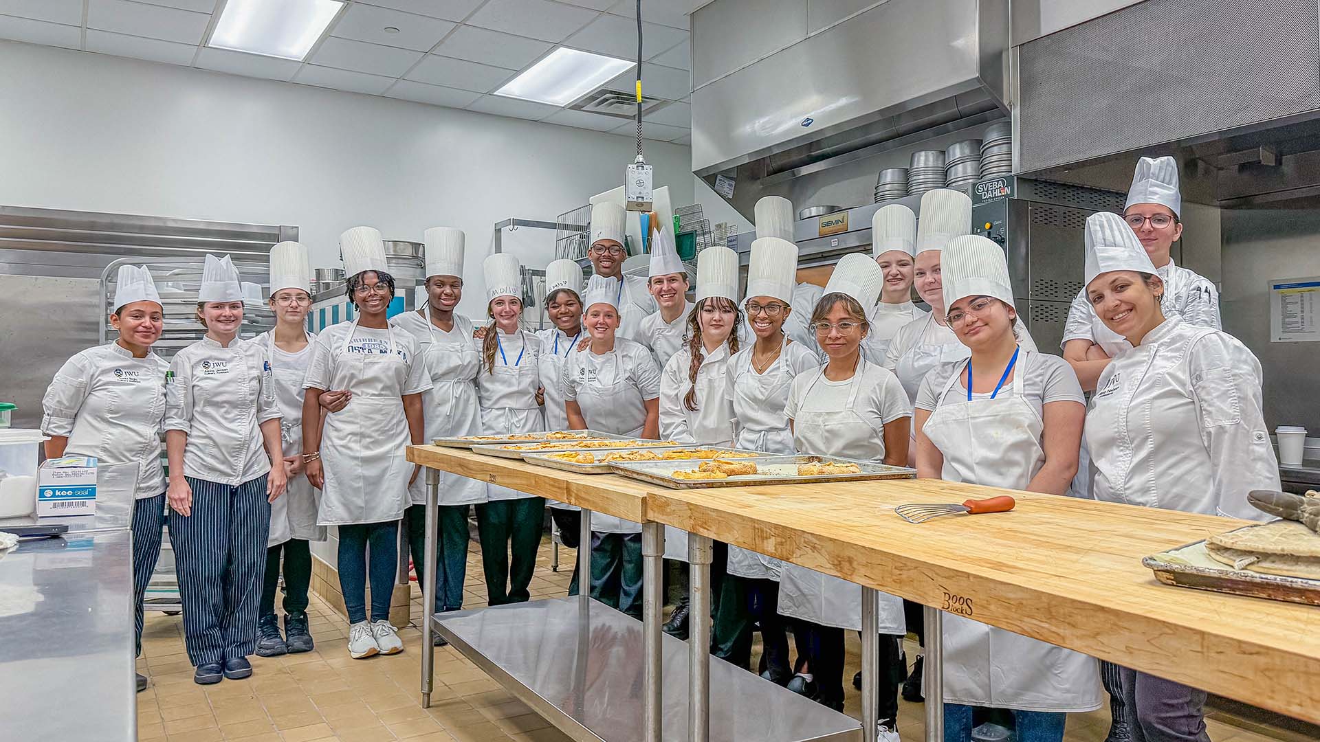 Group photo of the culinary cohort in a kitchen lab space.