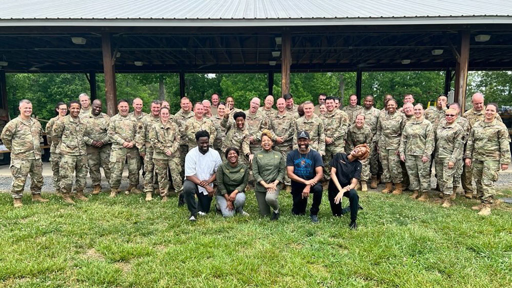 photo of a group of uniformed National Guard troops posing with the JWU alums who served them