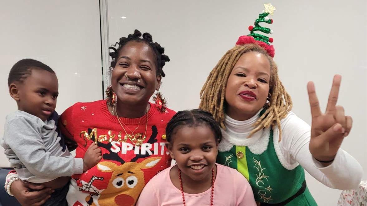 photo of two women in holiday clothing posing and smiling with two children