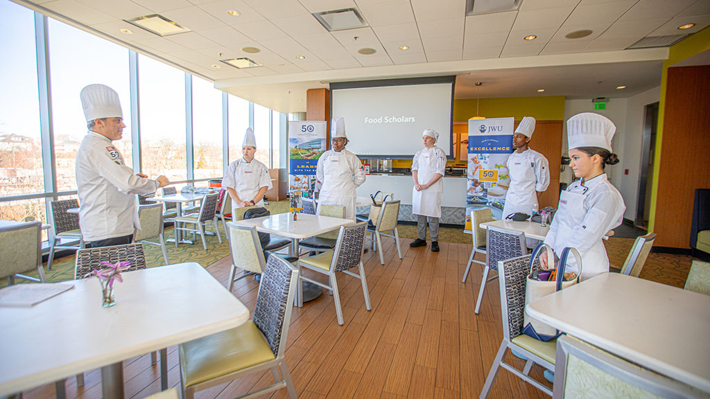 Scholarship finalists talking to JWU chef in a dining room.