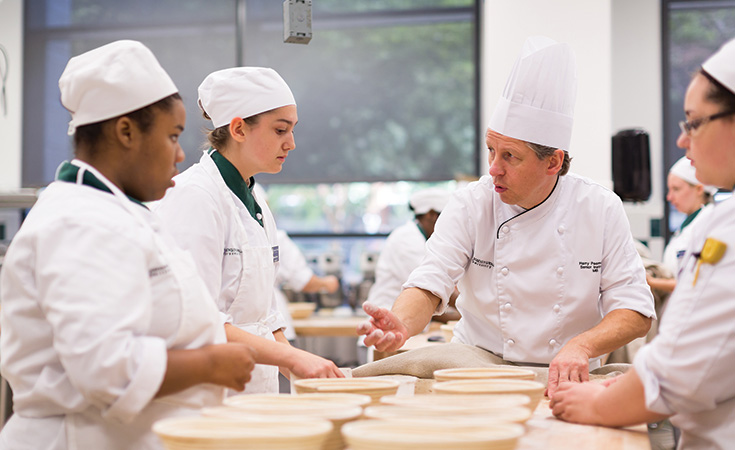 JWU Charlotte Students talking with a instructor during a lab.