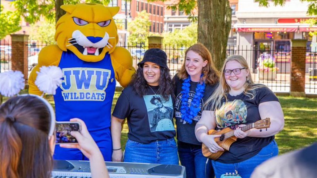 photo of Willie Wildcat mascot posing on campus with several students